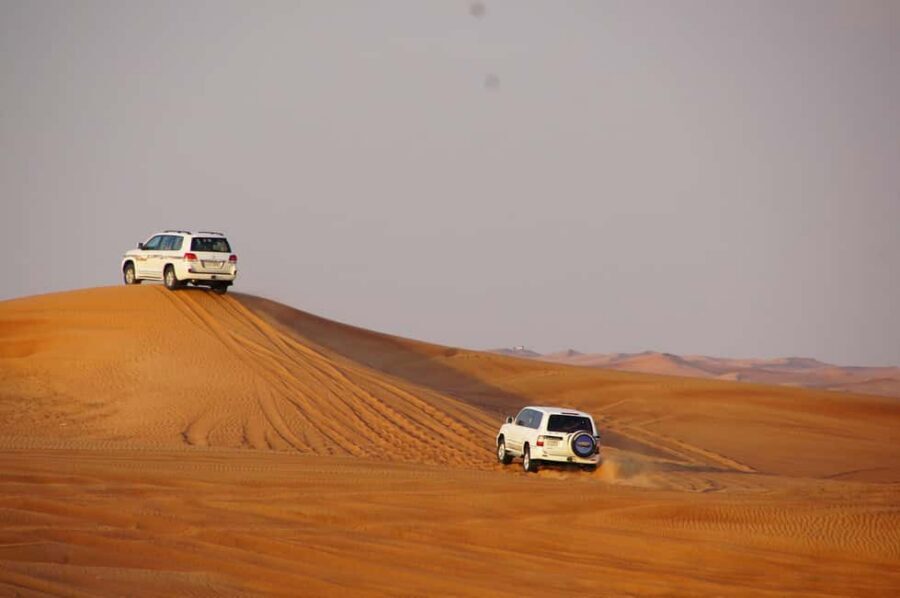 Dubai: Desert Safari, Camel, Quad Ride & Mesmerizing Shows - Desert camp setup: cushions, stage center, and an actual dinner